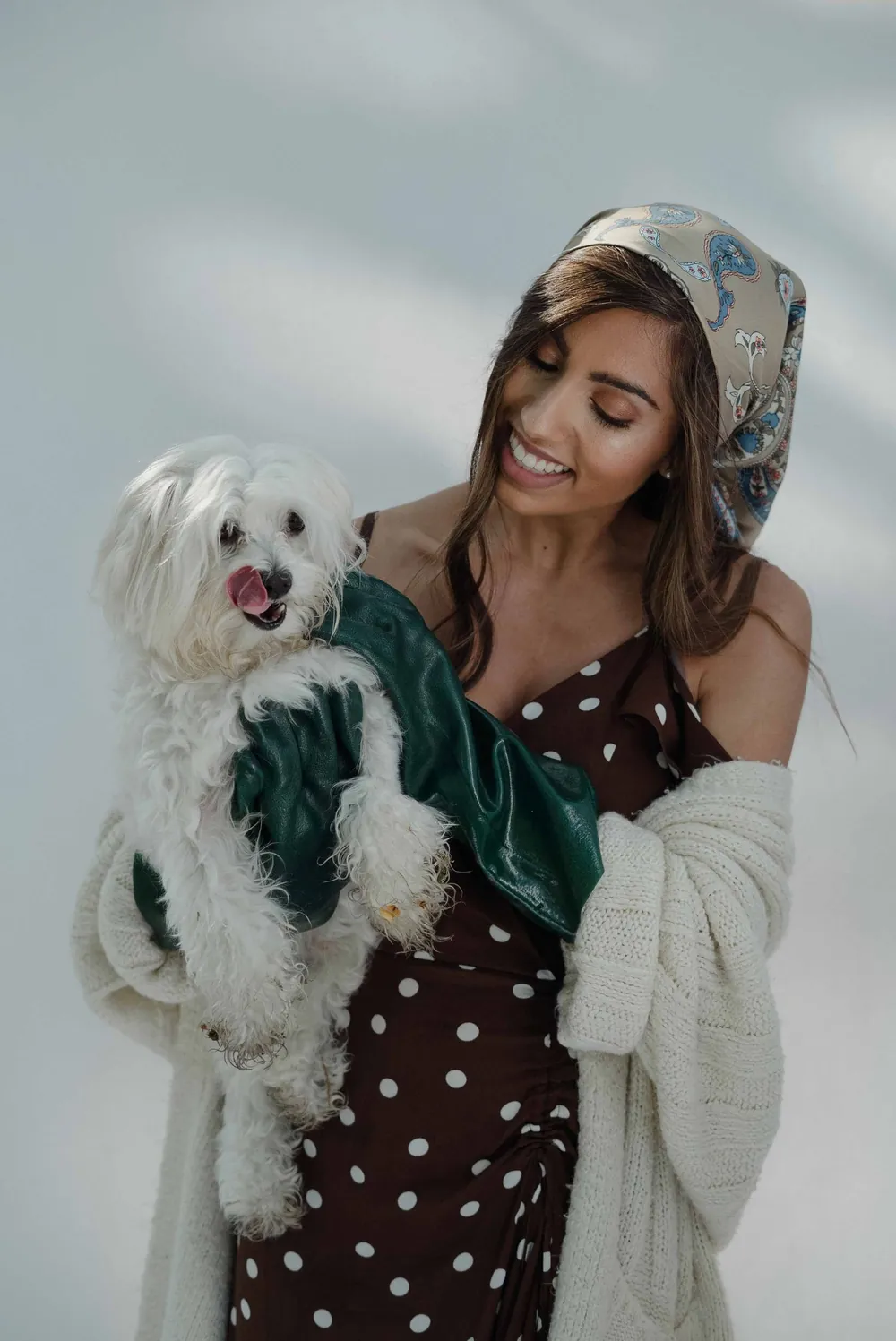Une femme souriante tient un bichon blanc dans ses bras.
